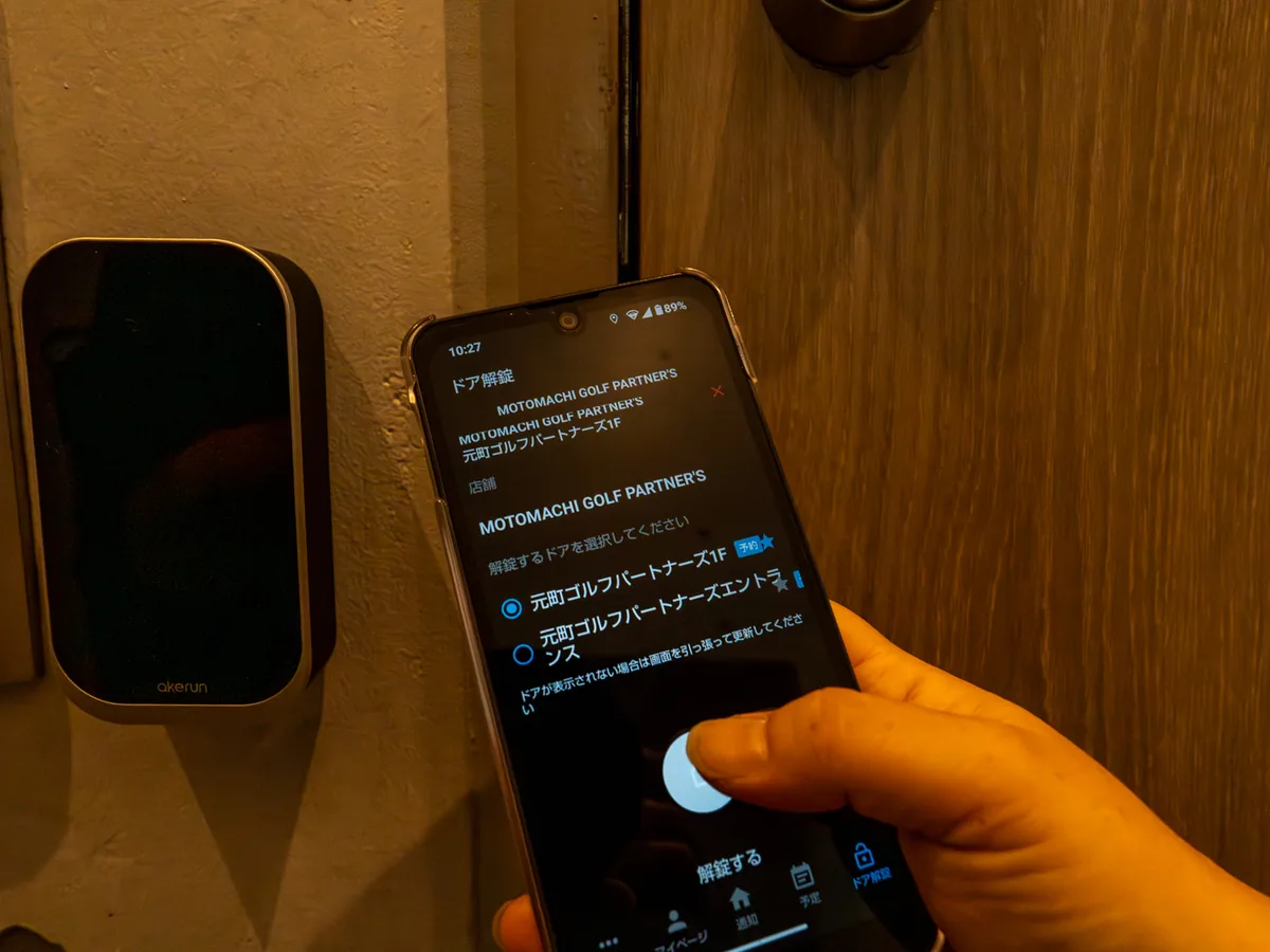 スマートロック『Akerun』の前で会員アプリの解錠画面を操作する様子